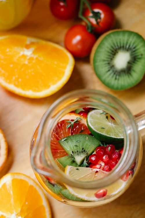 Free Refreshing glass pitcher of assorted citrus and kiwi fruits with pomegranate seeds, perfect for a healthy drink. Stock Photo