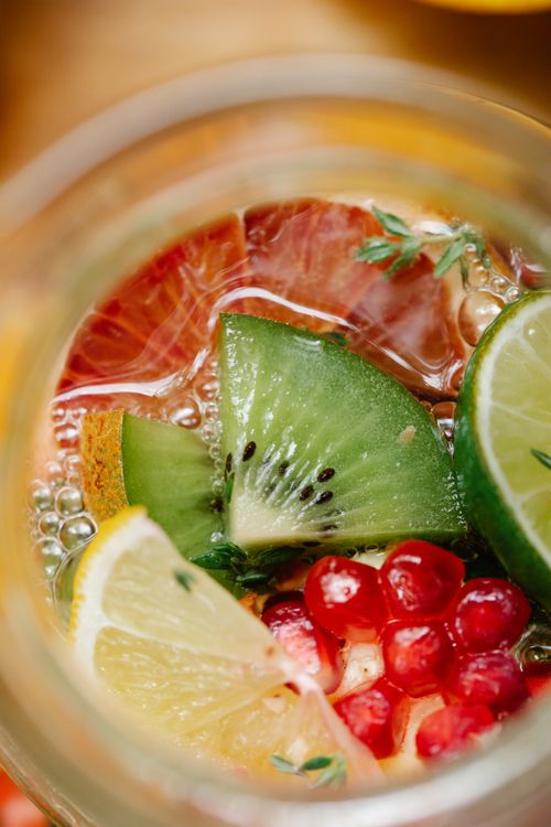 Free Close-up shot of a refreshing drink with kiwi, lemon, lime, and pomegranate. Perfect for healthy hydration. Stock Photo