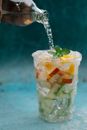 Pouring Liquid on a Cup with Sliced Fruits