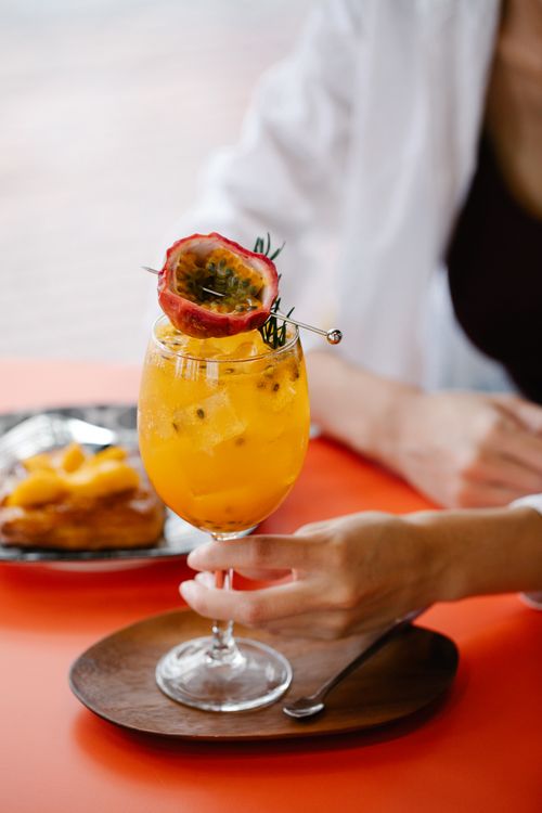 Free Vibrant passion fruit cocktail held above a wooden platter, perfect refreshment for a summer day. Stock Photo
