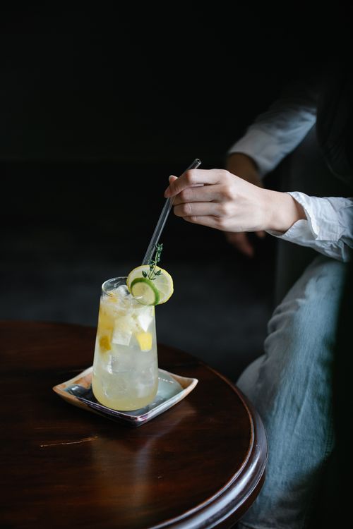 Free Close-up of a refreshing lemonade with ice, lemon, and cucumber, stirred by hand indoors. Stock Photo