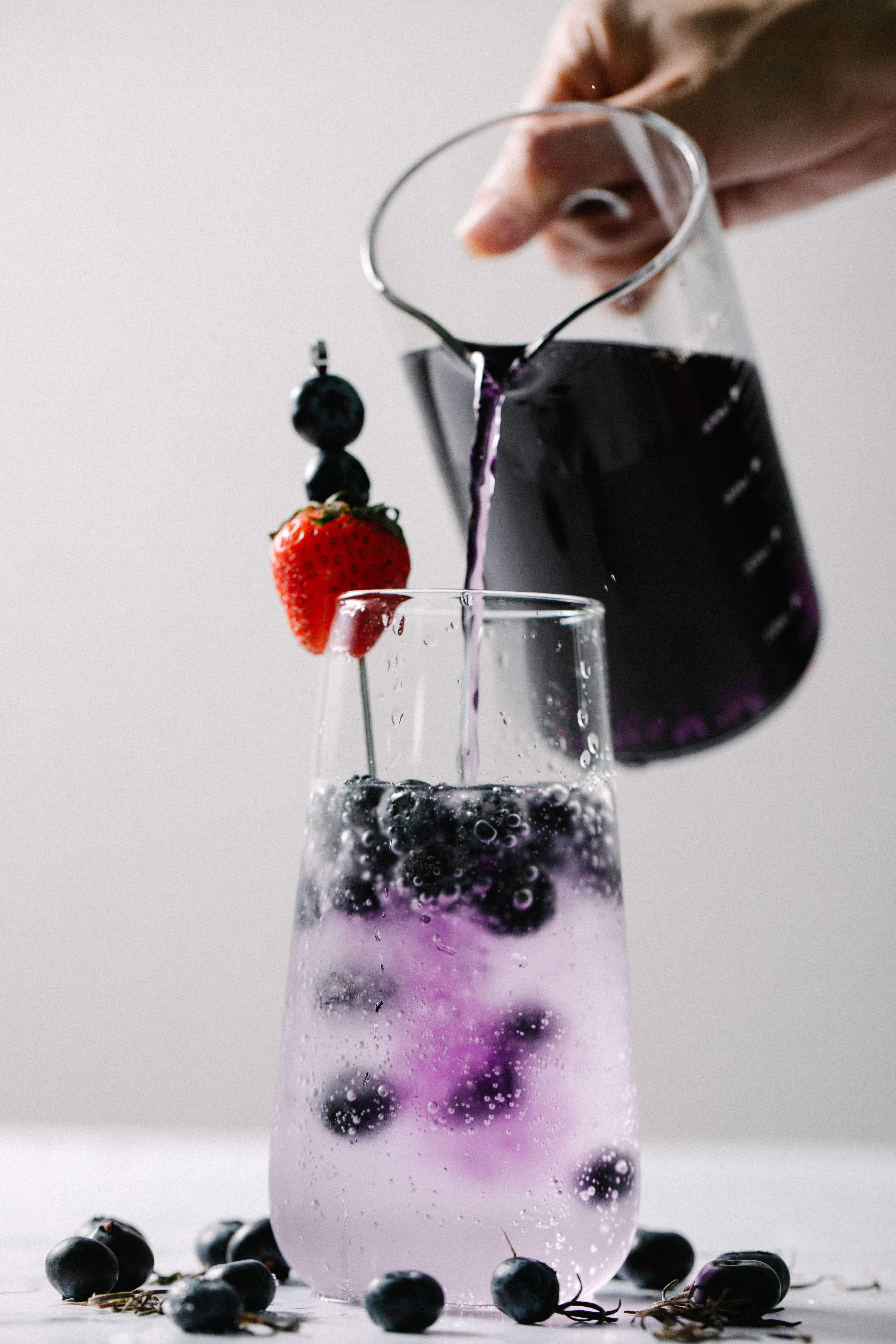 A close-up of a refreshing cocktail with blueberries and strawberries, poured with precision.