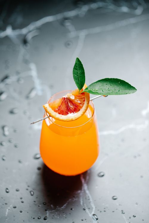 Free Close-up of a fresh orange juice garnished with blood orange slice on a metallic surface. Stock Photo