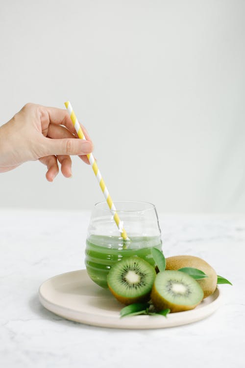 Close-Up Shot of a Person Stirring a Glass of Kiwi Drink