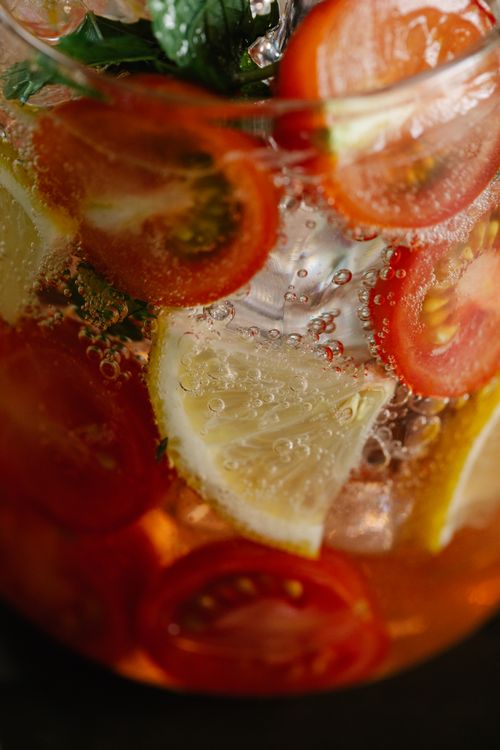 Free Close-up view of a refreshing citrus drink with sliced lemon and cherry tomatoes. Stock Photo