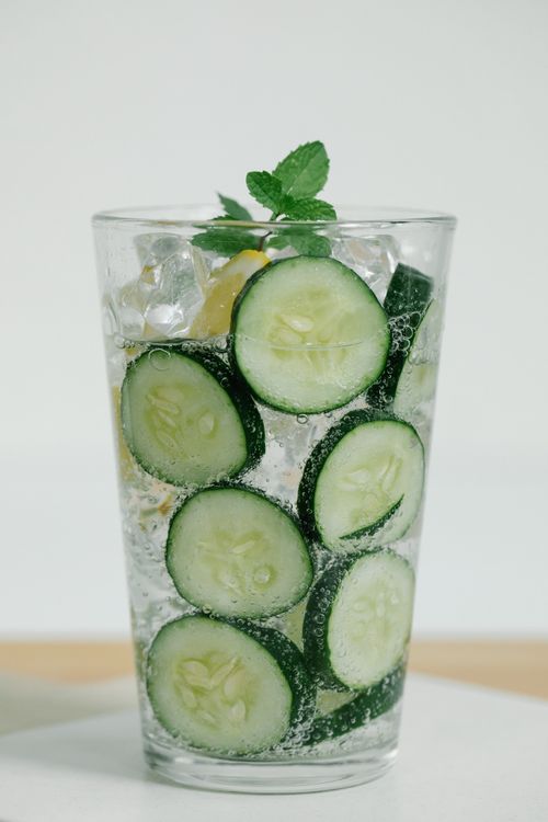 Close-up of sparkling water infused with cucumber and mint slices in a clear glass