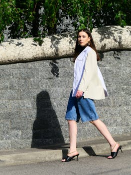 Stylish woman in denim and blazer walking confidently outdoors.