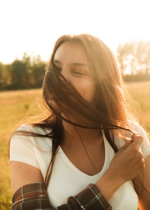 Free A Woman in White Shirt Holding Her Hair Stock Photo