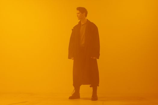 Man in black coat standing against an orange background, embodying a cyberpunk retro-futuristic style.