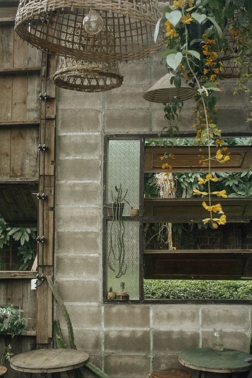 Free Rustic café with exposed concrete walls and hanging lights surrounded by lush greenery. Stock Photo