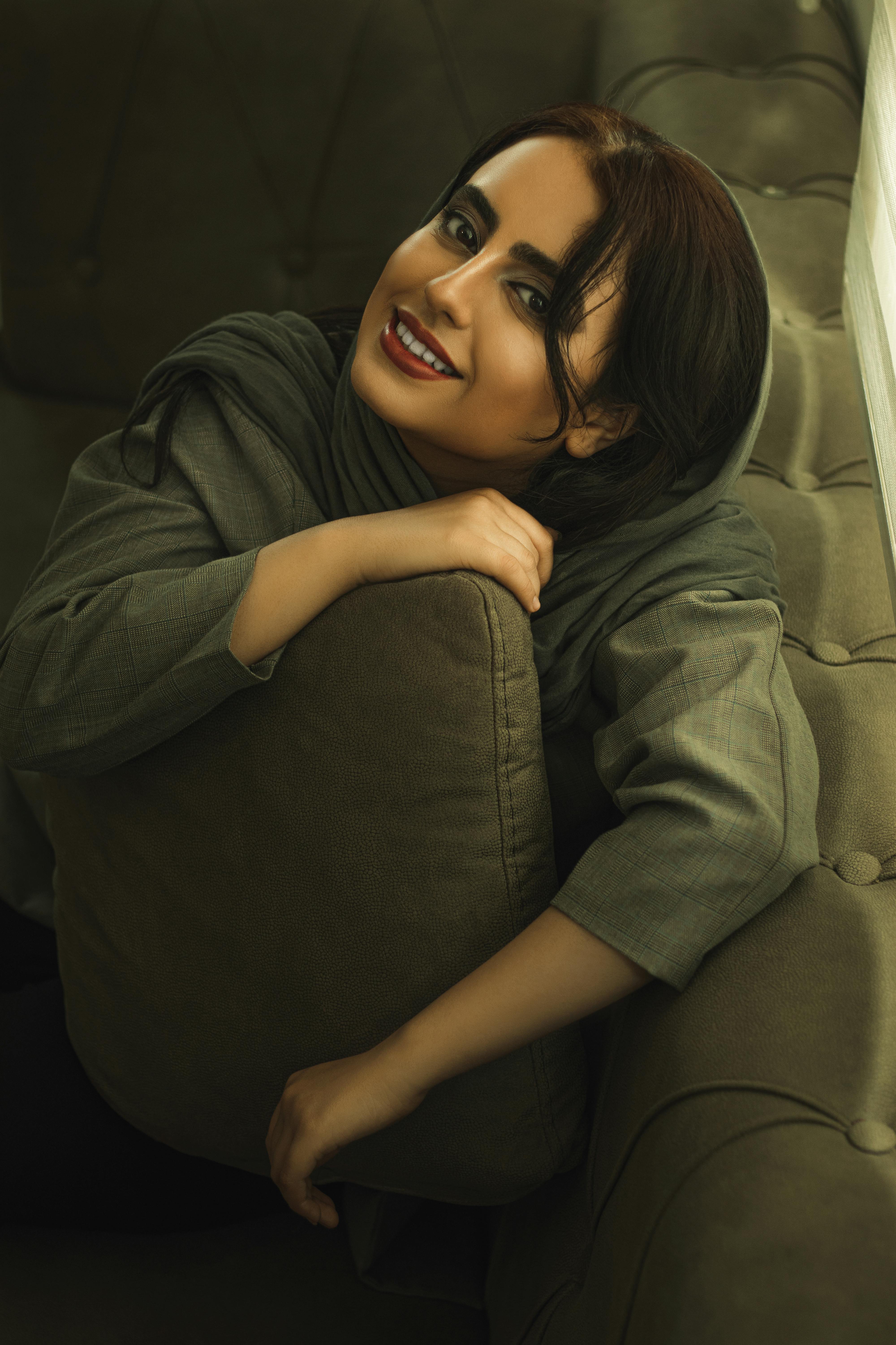 A joyful woman in a cozy indoor setting in Mashhad, Iran. Embracing comfort.