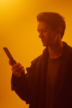 Moody portrait of a man using a flip phone in dystopian lighting.