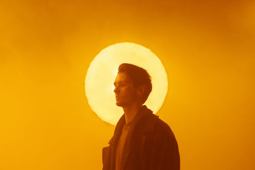 Silhouette of a man against a glowing circle creating a mysterious and warm atmosphere.