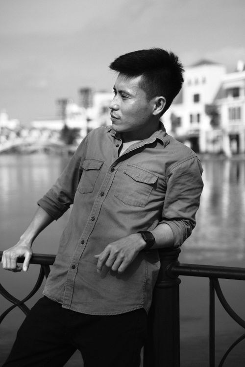 Free Grayscale image of a stylish man posing near a waterfront in Vietnam, exuding confidence. Stock Photo