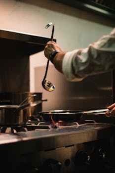Chef using a ladle on a stove in a restaurant kitchen, Dubai.