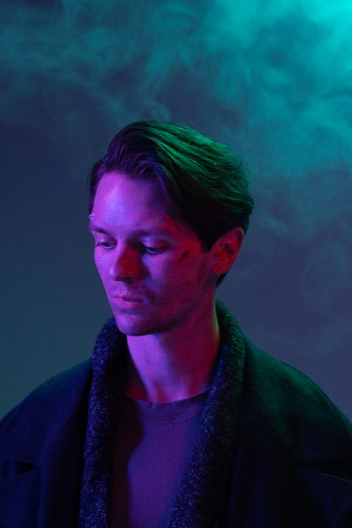 Free Close-up portrait of a man illuminated by vibrant neon lights with smoke background, creating a cyberpunk style. Stock Photo