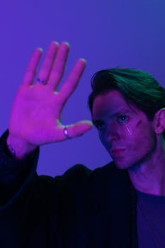Striking portrait of a man in neon light, conveying a cyberpunk theme with a raised hand gesture.