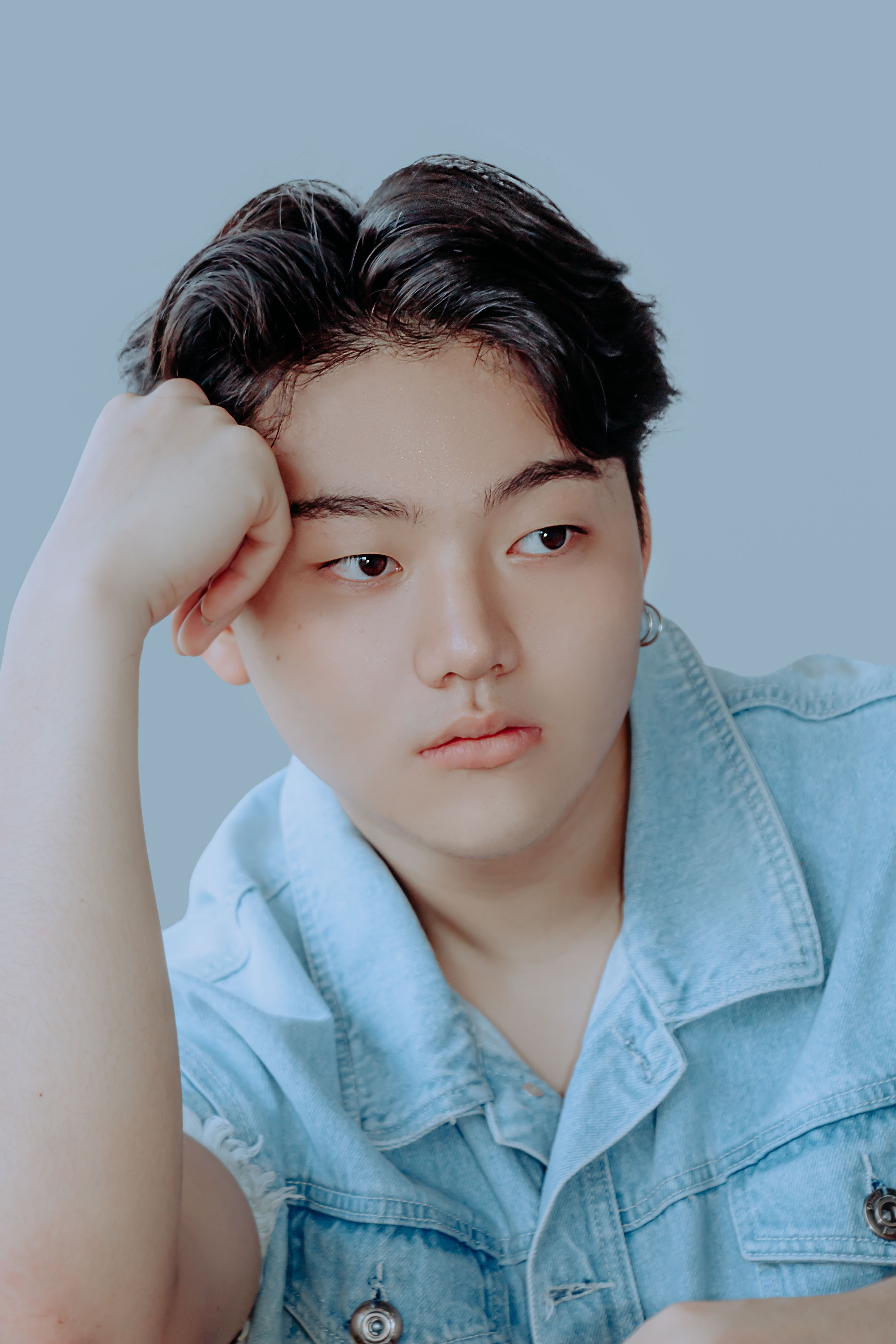 Portrait of an Asian teenager in a denim shirt looking thoughtful. Perfect for stock photography.