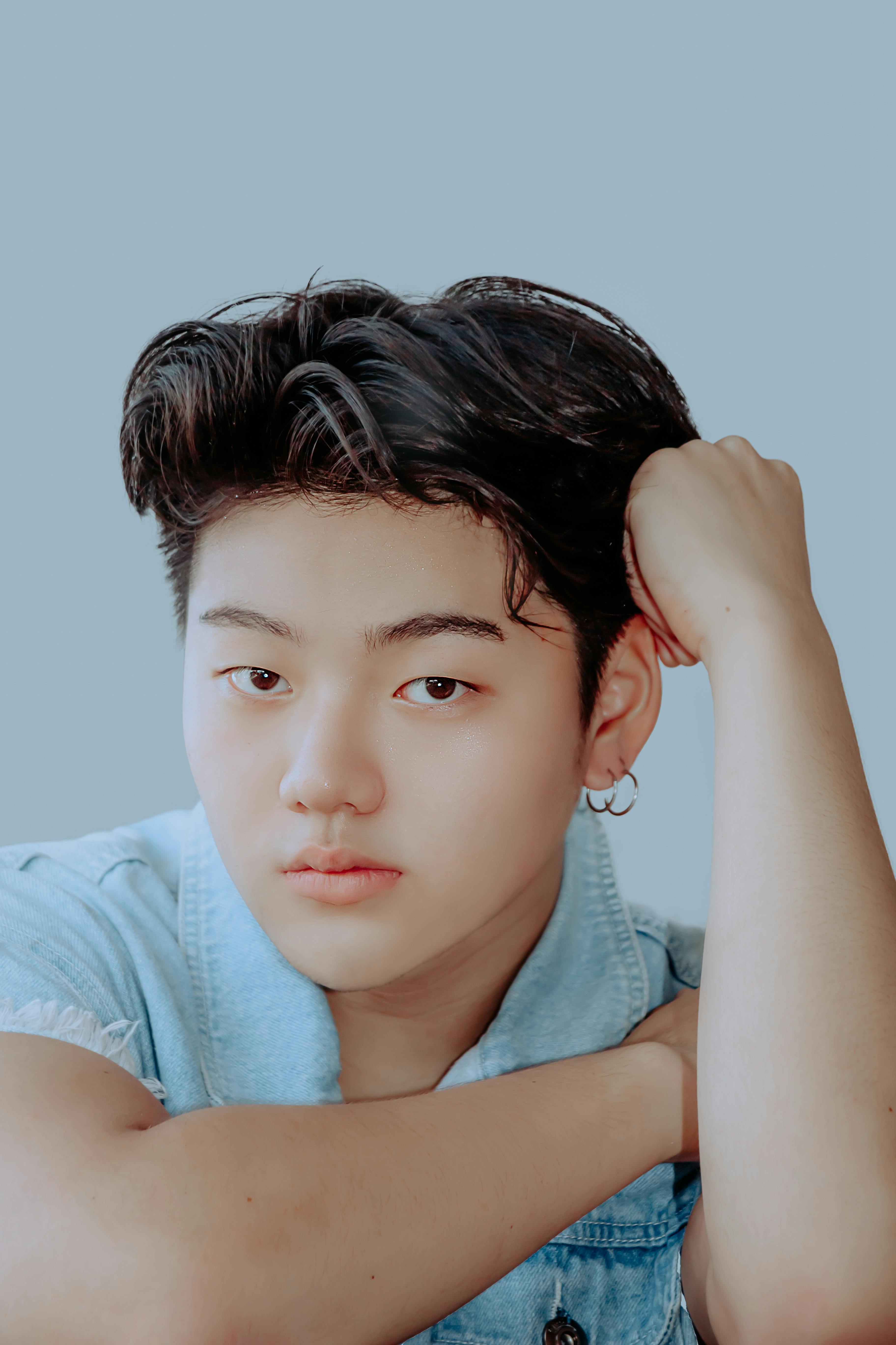 Close-up portrait of a serious young Asian teenager in a denim shirt.