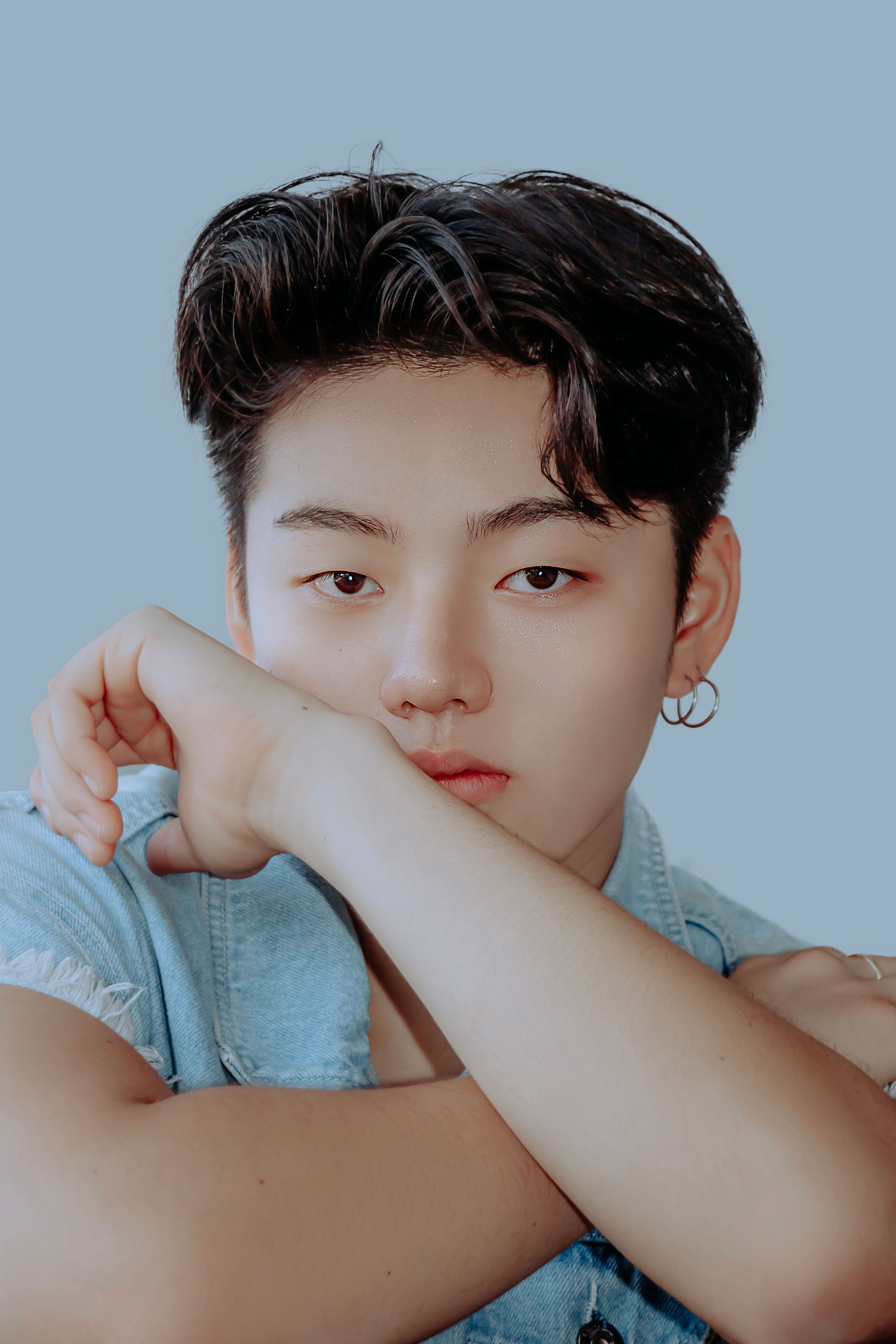 Young Asian teenager wearing a denim shirt with a serious expression, captured in a close-up portrait.