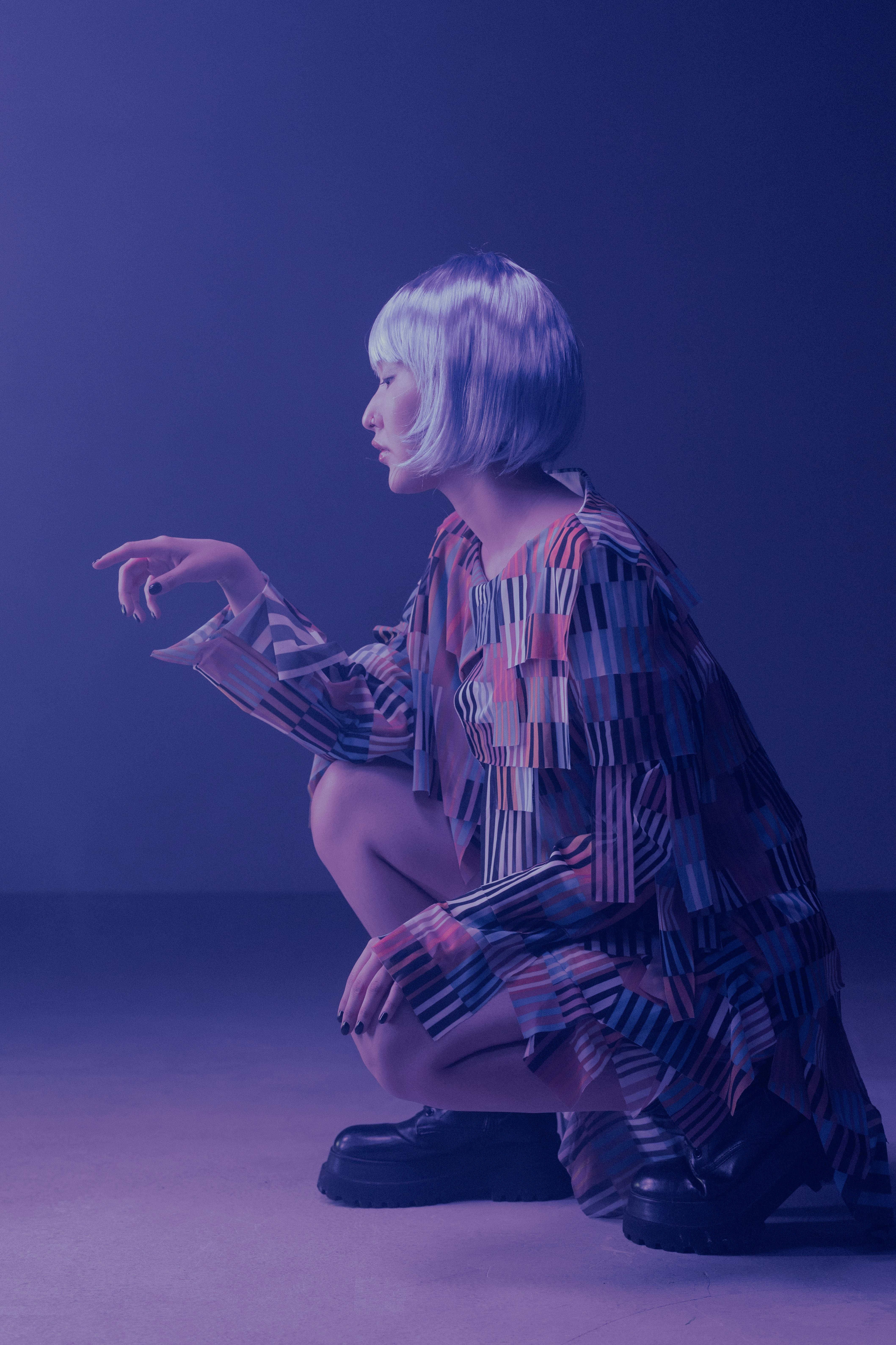 Young woman in futuristic attire under purple lighting, exuding a cyberpunk fashion vibe.