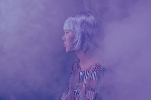 Side view of a fashionable woman in a smoky, conceptual studio setting.