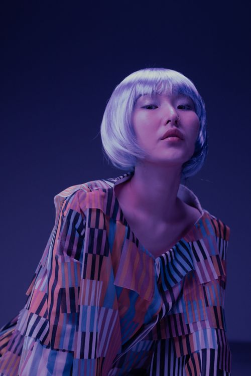 Free A striking portrait of a woman wearing a colorful striped dress with a futuristic and cyberpunk vibe. Stock Photo