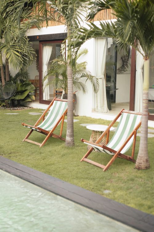 Free Relaxing poolside area with lounge chairs and palm trees in a tropical setting. Stock Photo