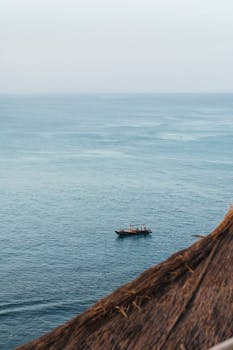 A peaceful ocean view with a solitary boat captured at dawn, providing a tranquil seascape scene.