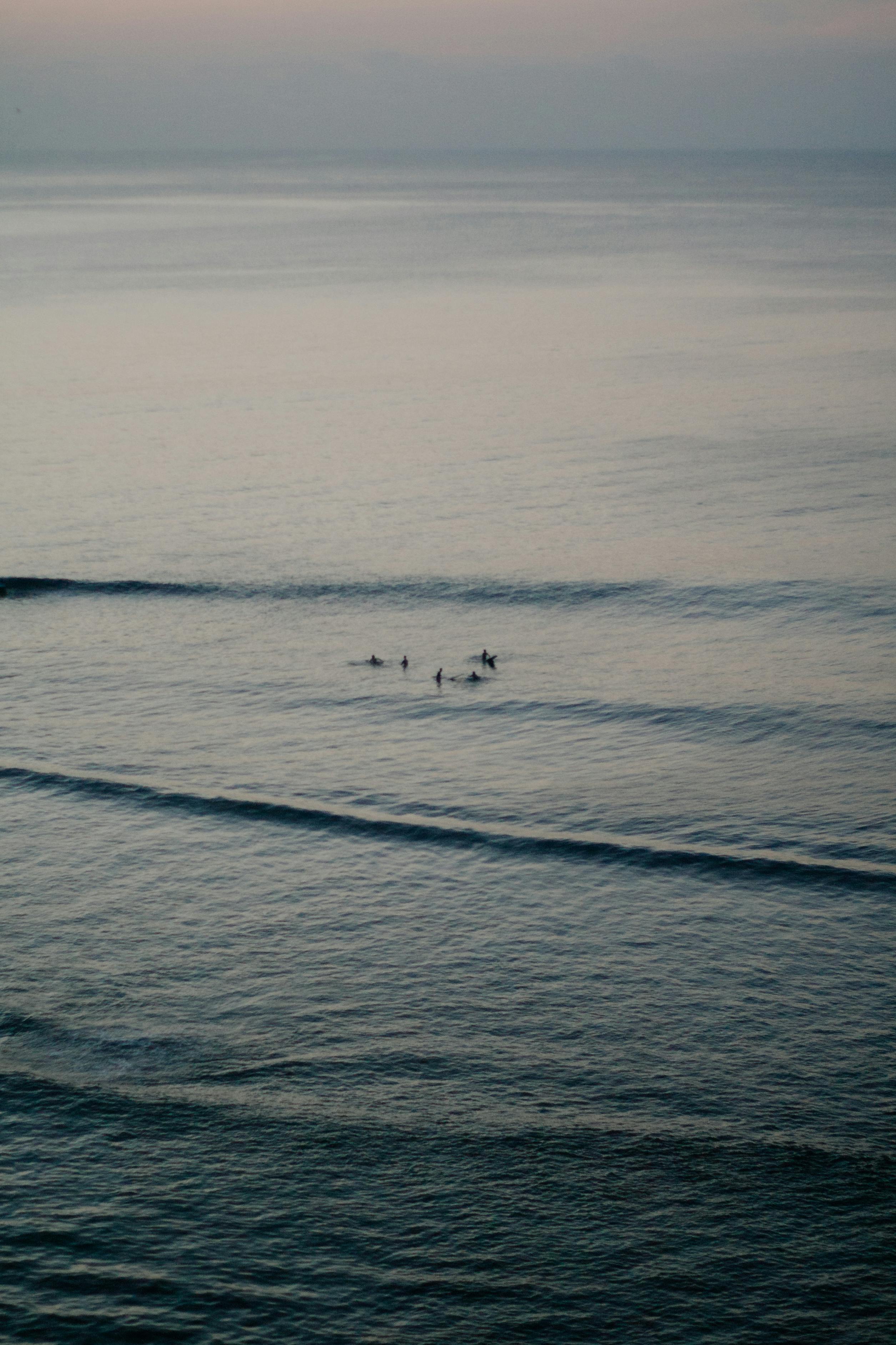 Aerial view of surfers riding gentle waves during a tranquil evening.