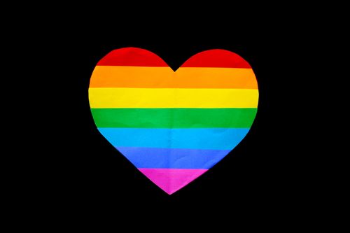 Free Colorful heart shape with rainbow stripes against a black background, representing LGBT pride and diversity. Stock Photo