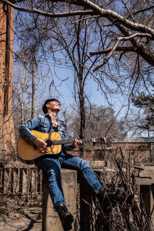 Free A man enjoying playing guitar outside in a sunny, autumn setting. Stock Photo
