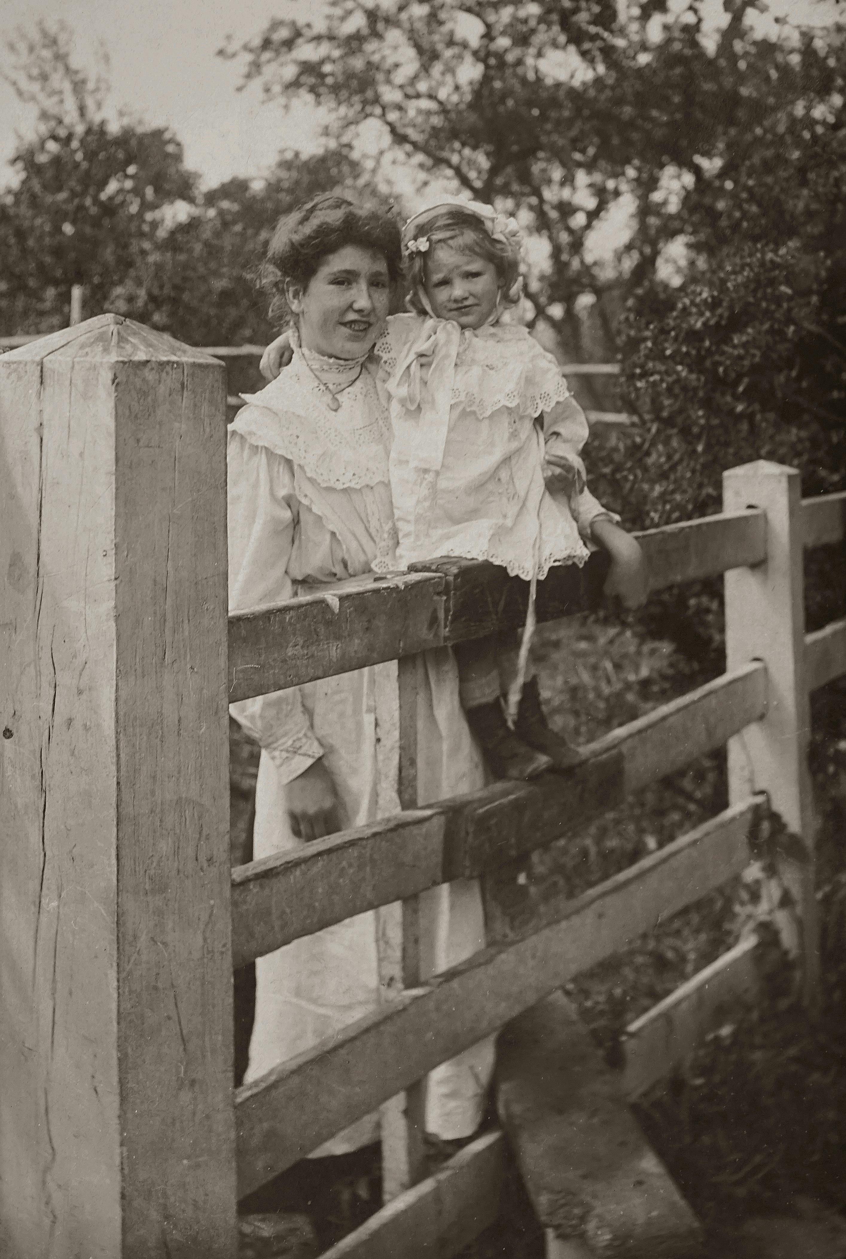 classic photo of mother and daughter posing near a wooden fence