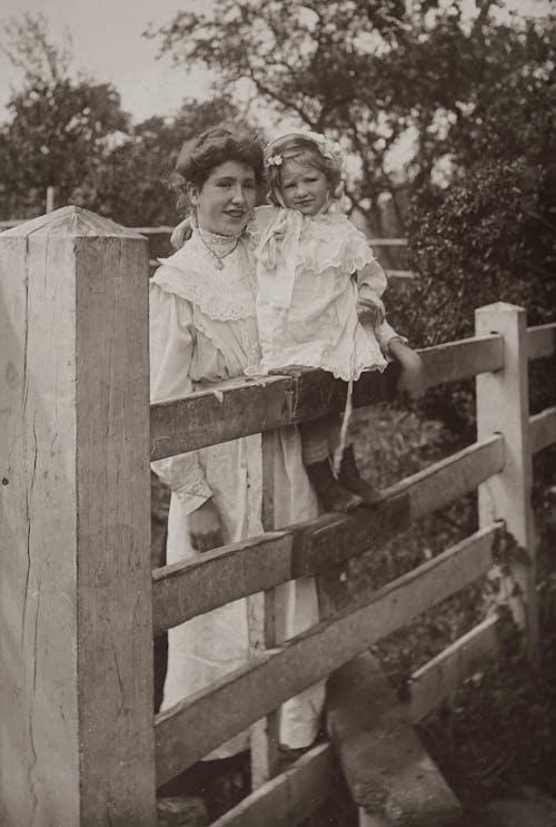 Classic Photo Of Mother And Daughter Posing Near A Wooden Fence