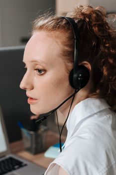 Side view of a woman using a headset while working indoors, conveying focus and professionalism.