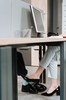 A playful moment between colleagues with foot contact under the office desk.