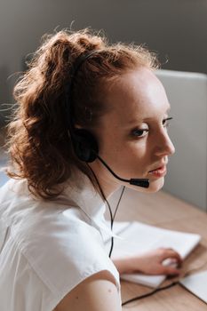Professional woman at a work desk using a headset, focused on tasks.
