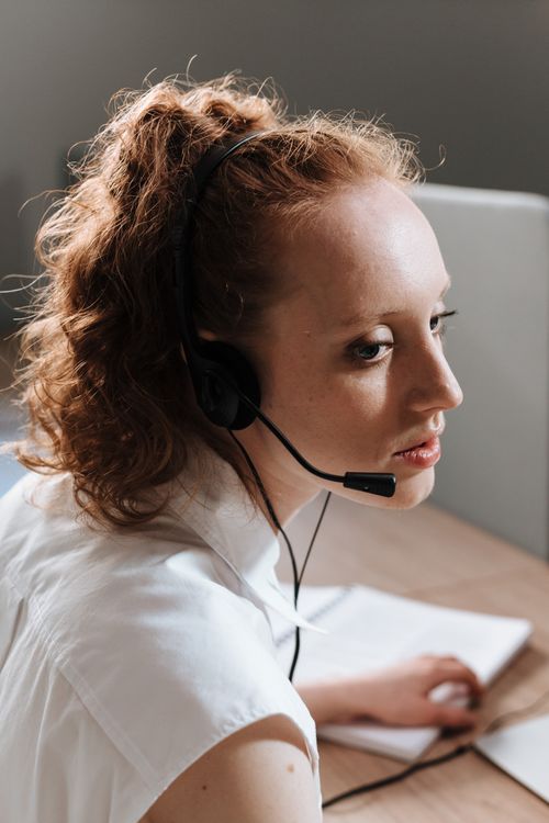 Free Professional woman at a work desk using a headset, focused on tasks. Stock Photo