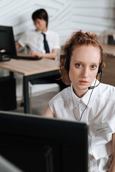 Businesswoman with headset working at a computer in an office setting, focusing on customer service.