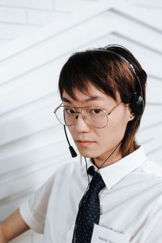 Serious call center agent with eyeglasses and headset in a professional setting, focused on work.