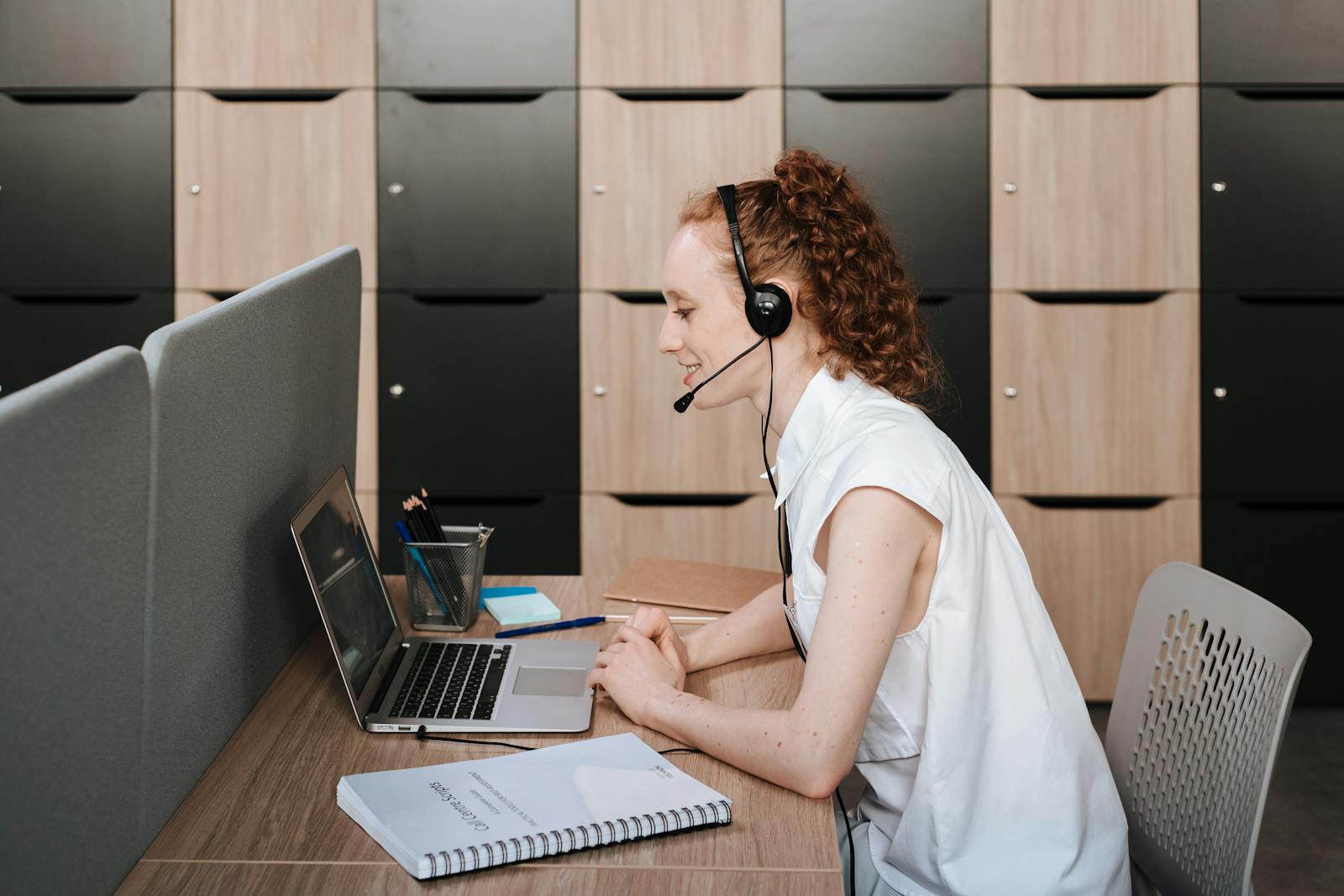 A tutor on a video call wearing a headset at a laptop