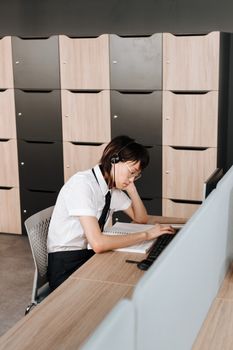 Professional call center agent at desk in modern office, wearing headset and typing.