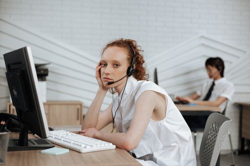 Free Focused call center agent with headset working at a modern office desk. Stock Photo