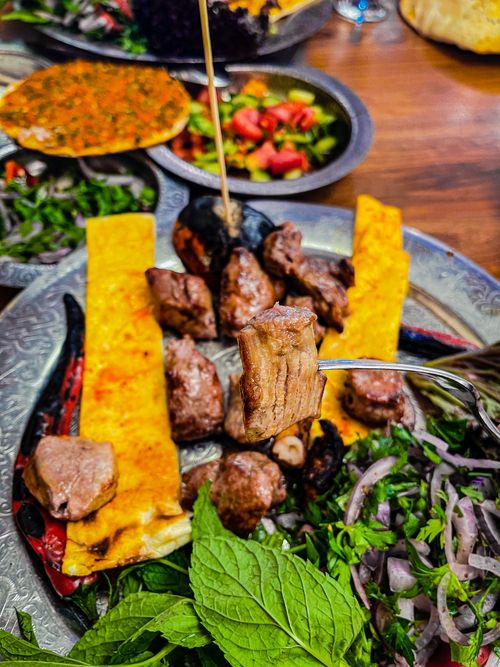 Free Savory grilled meat served with traditional bread, fresh salad, and herbs for a flavorful meal. Stock Photo