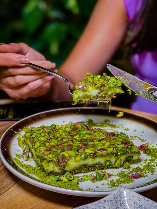 Free A close-up of a pistachio dessert being served on a plate, showcasing its vibrant colors and textures. Stock Photo