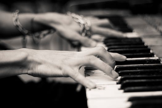 Cinematic close-up of hands playing piano in monochrome, creating a moody musical ambiance.
