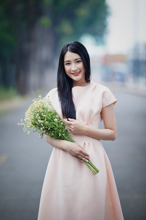 A Beautiful Woman in a Dress Carrying a Bouquet of Flowers