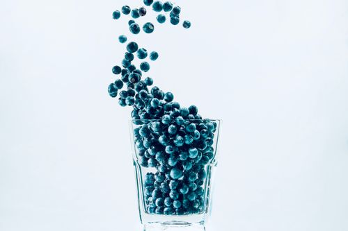 Free Vibrant blueberries cascading into a glass against a clear, white background. Stock Photo
