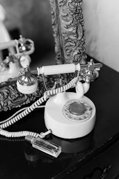 Black and white photo of a vintage rotary phone with a baroque frame reflection.