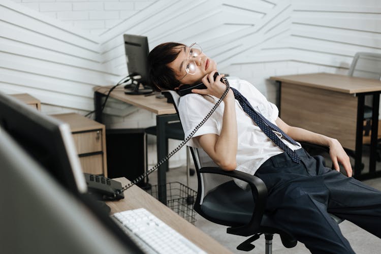 A Man With Eyeglasses Talking On The Telephone